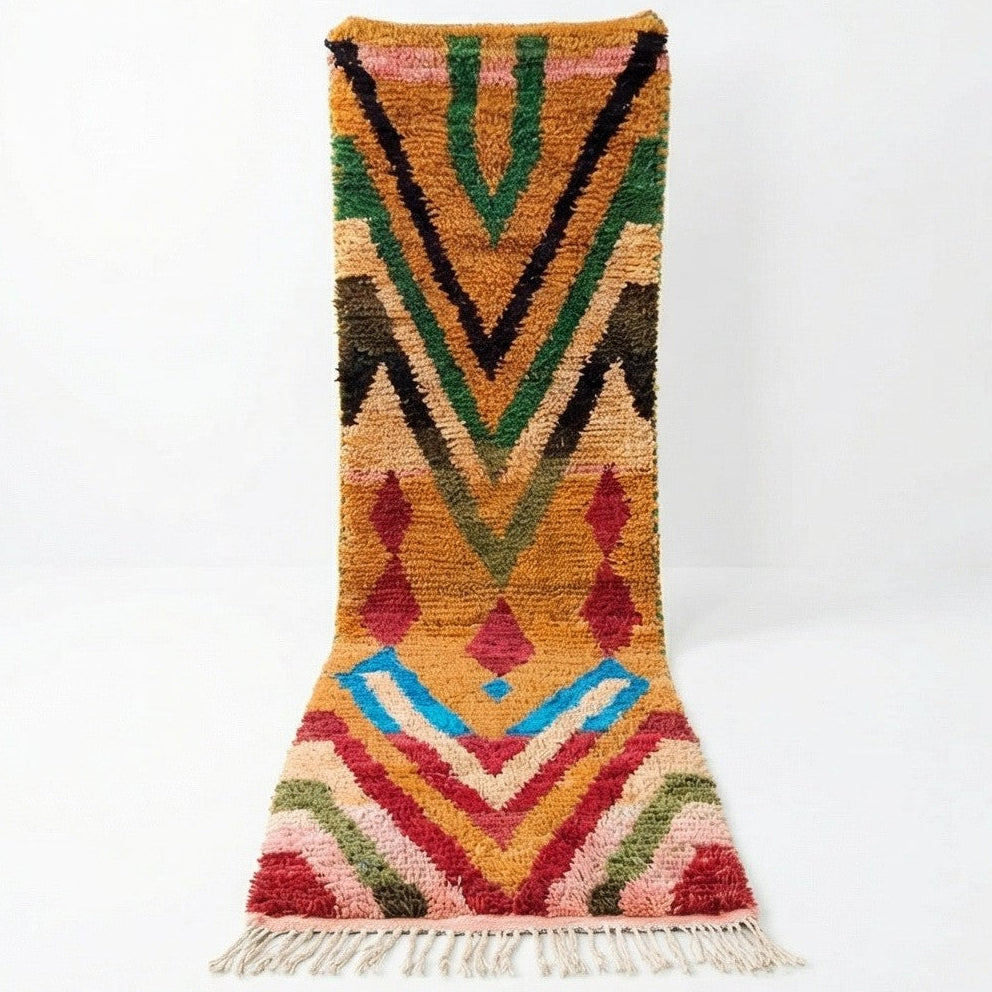 Tapis couloir berbère Boujad à fond ocre, avec des motifs géométriques en chevrons et losanges rouge, vert, noir et bleu, terminé par des franges.