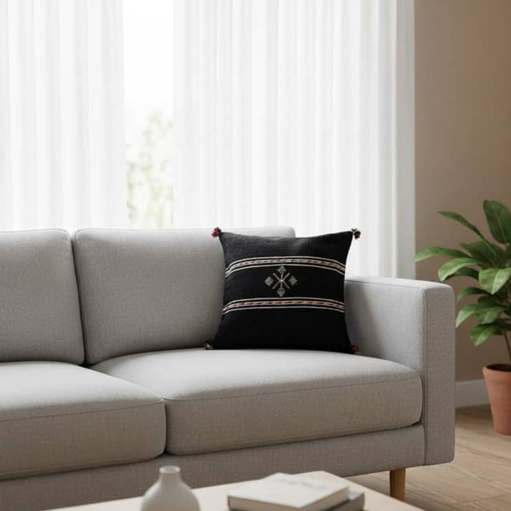 Coussin berbère noir en coton, de style ethnique avec motif brodé et pompons décoratifs.