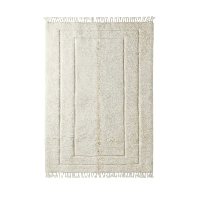 Grand tapis marocain en laine blanche, de style berbère, avec motifs géométriques en relief et franges.