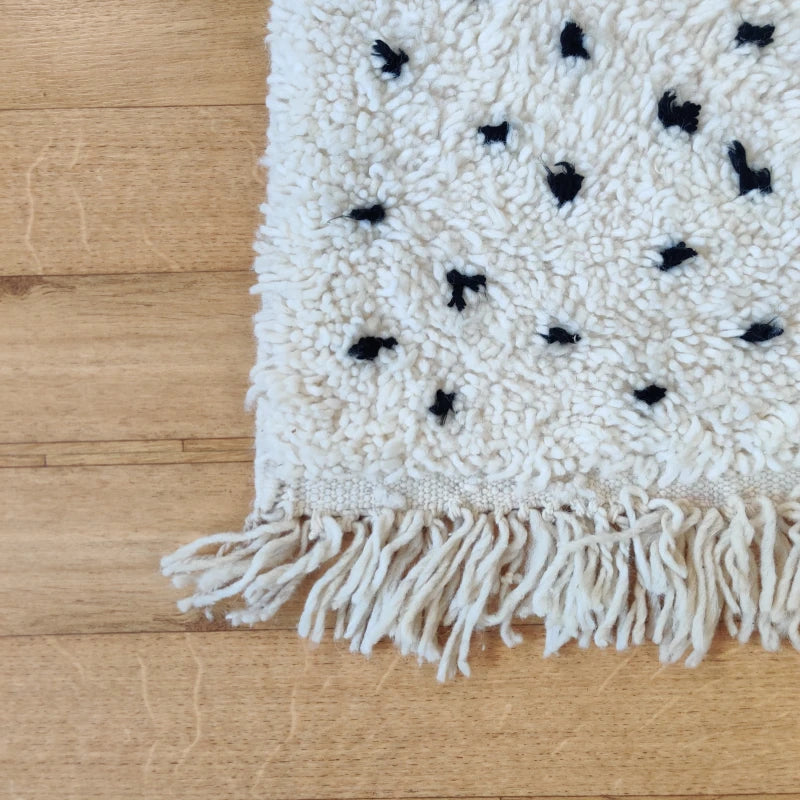 Gros plan sur les pois noirs du tapis Beni Ouarain, soulignant la qualité et le design unique.