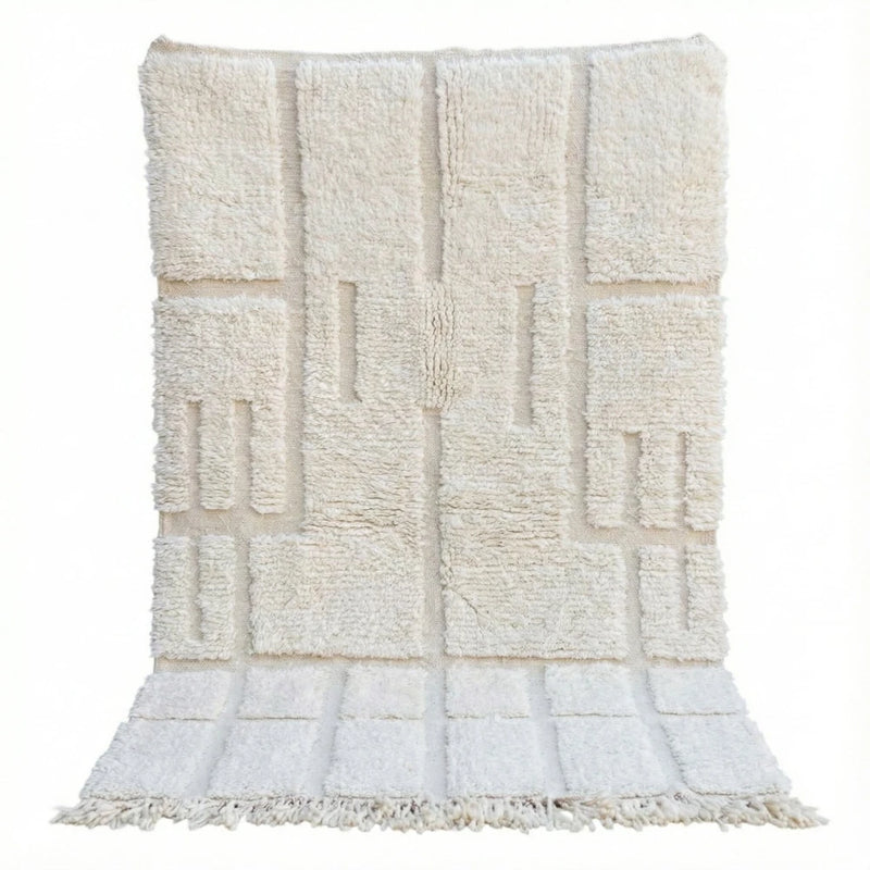 Tapis berbère blanc à motifs graphiques parsemés de lignes et de rectangles en relief, avec des franges en bas.