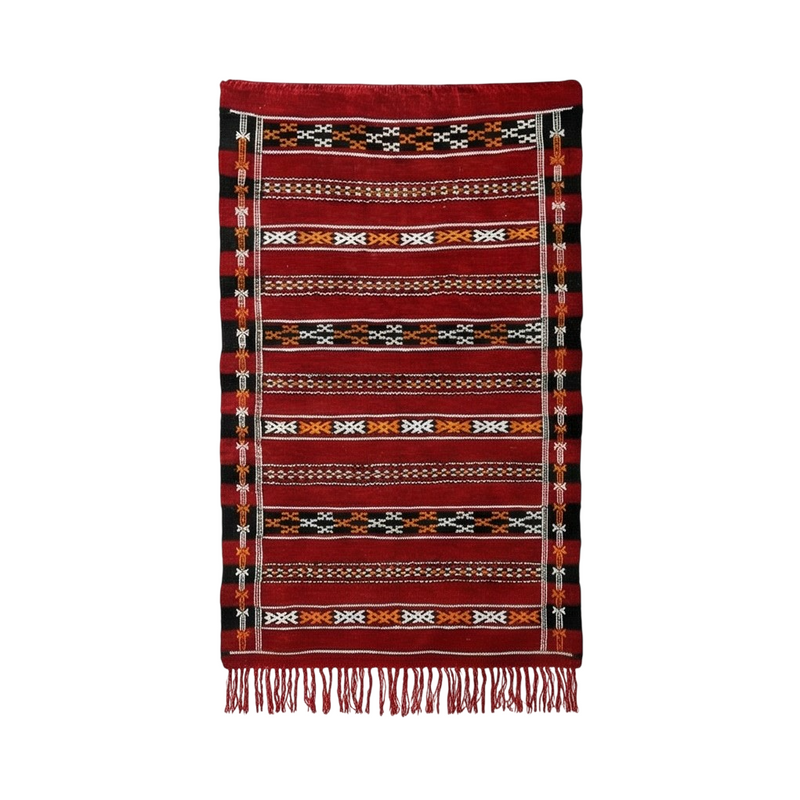 Petit tapis kilim rouge, de style ethnique marocain, avec motifs géométriques et franges décoratives.