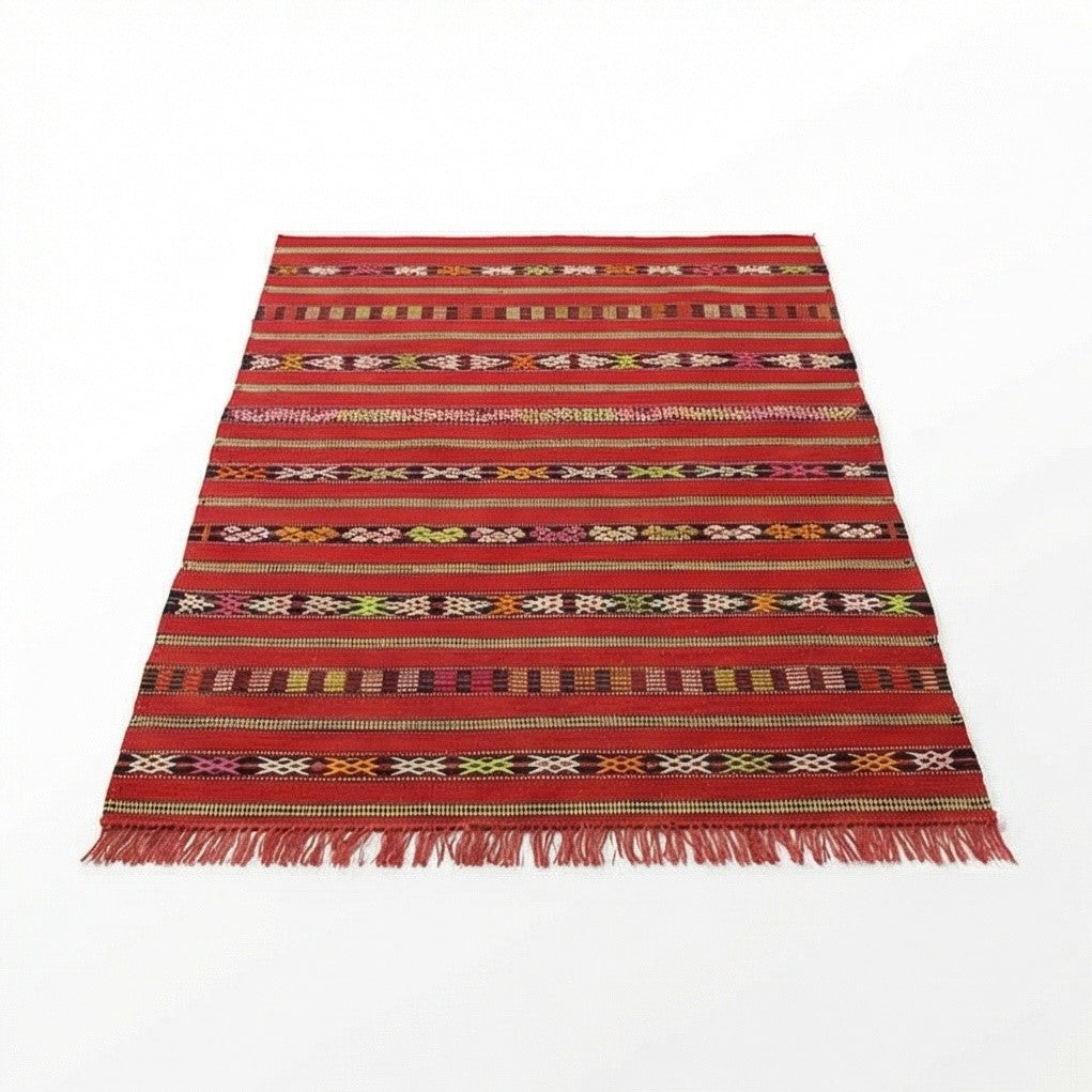Petit tapis kilim rouge marocain, de motifs géométriques rayés et franges décoratives.