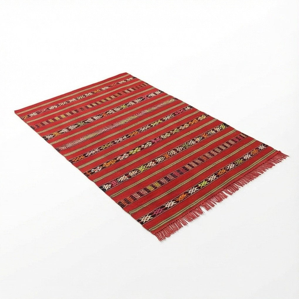 Petit tapis Kilim rouge de style marocain, à rayures et franges décoratives.