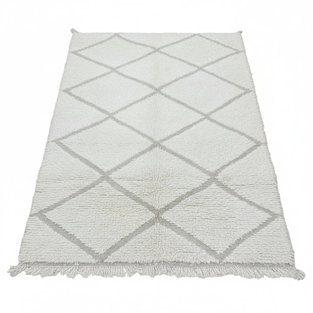 Tapis marocain blanc en laine à motif losanges, de style berbère, avec franges décoratives.