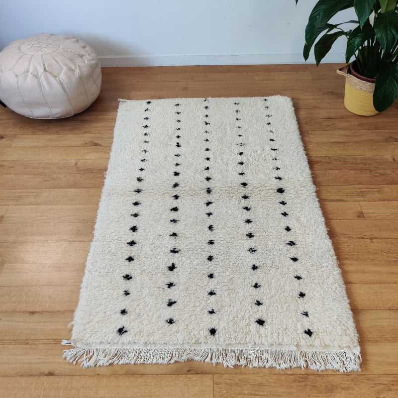 Tapis marocain compact en laine naturelle Beni Ouarain avec design à pois noirs.
