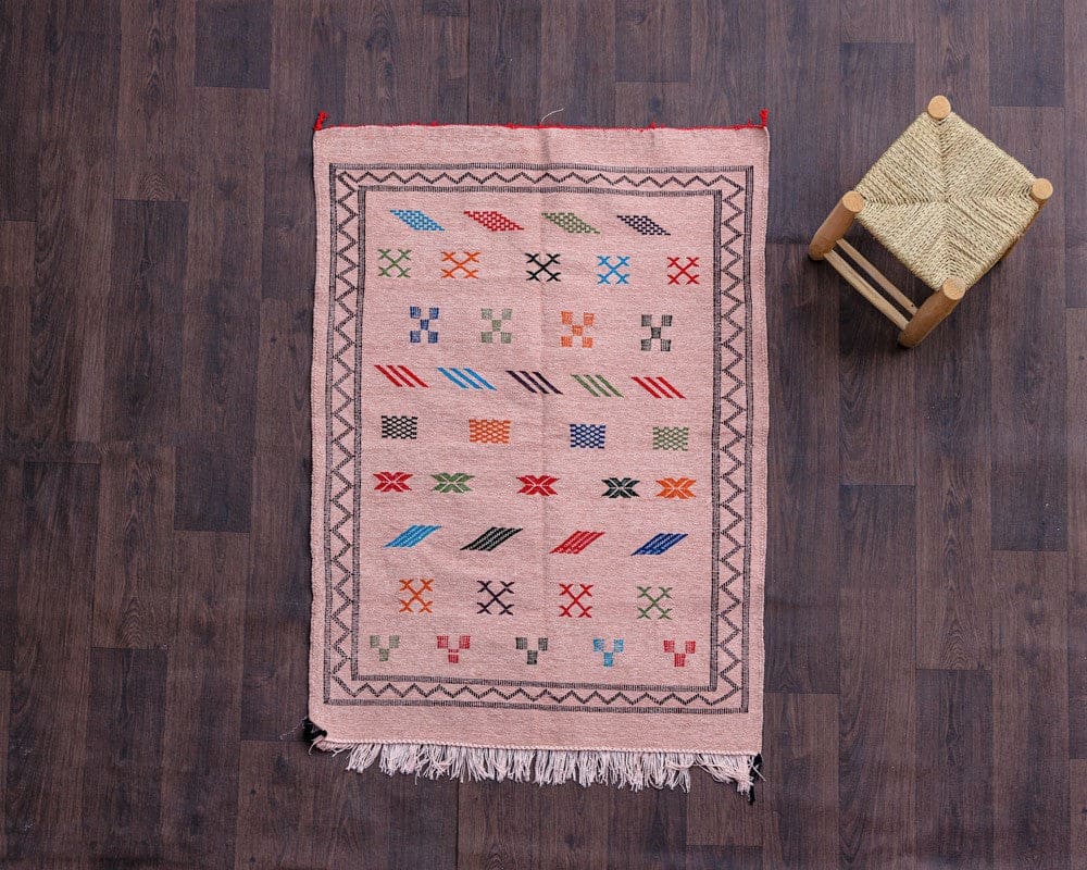tapis boheme rose a coté d'un petit tabouret berbere