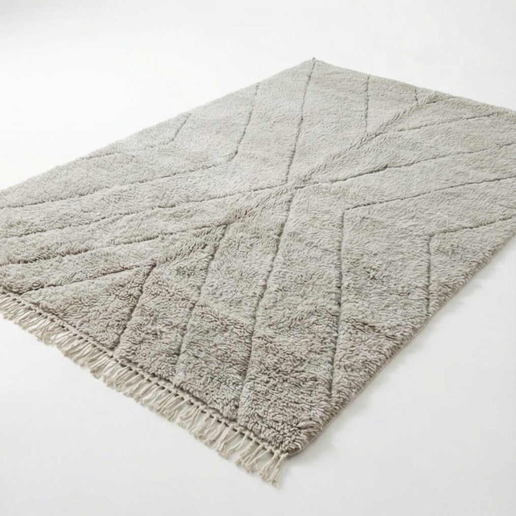 Grand tapis marocain gris en laine, de style berbère, avec motif géométrique en relief et franges.