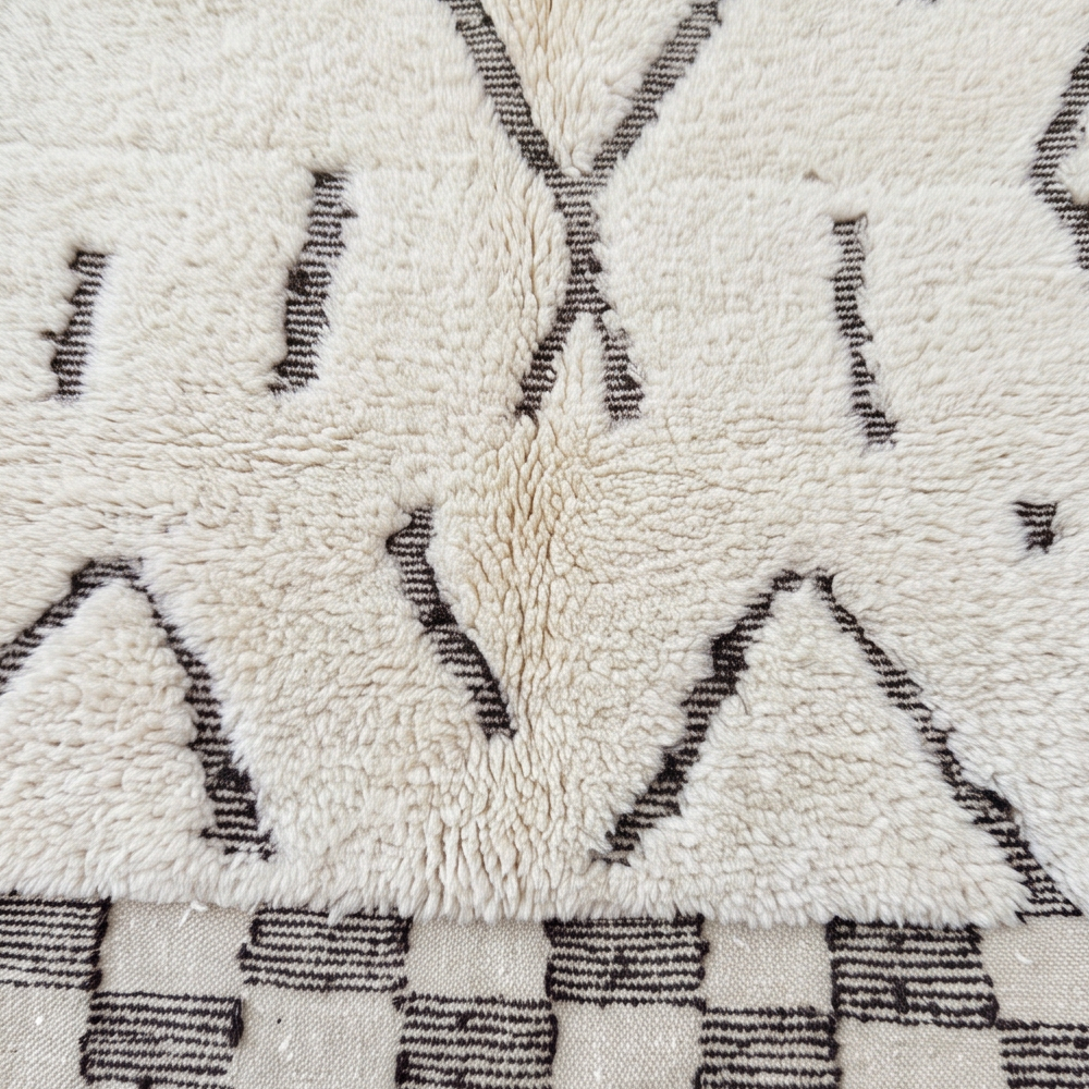 Gros plan sur la laine et les motifs abstraits bruns du tapis Béni Ouarain