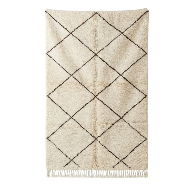 Tapis berbère crème à losanges noirs, texture moelleuse et franges.