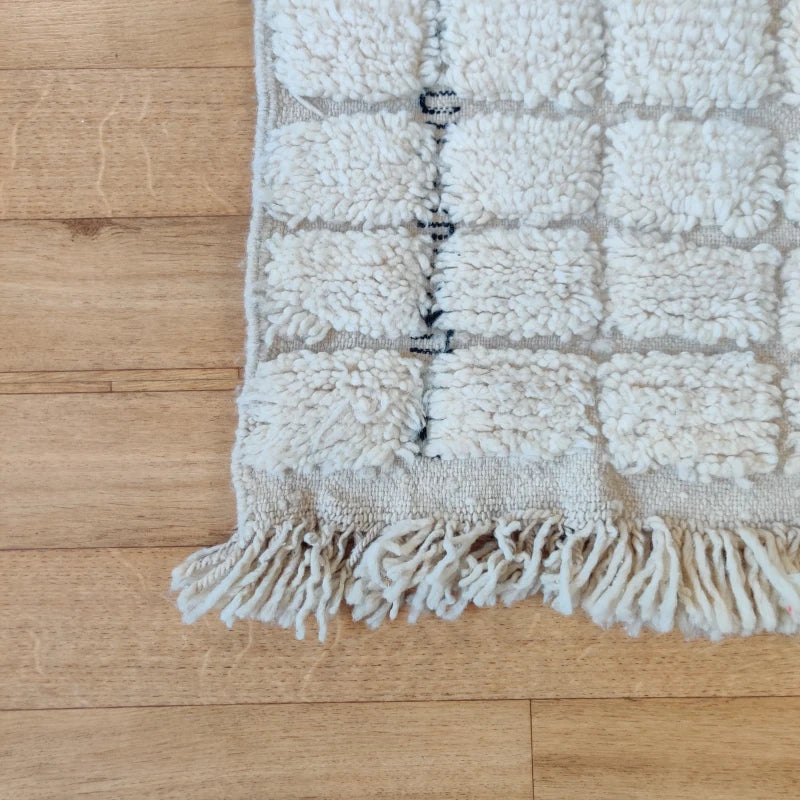Gros plan sur le motif à carreaux blancs du tapis berbère, symbole d'artisanat marocain authentique