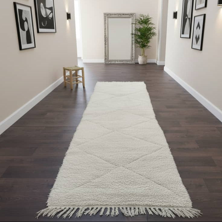 Tapis berbère de couloir blanc cassé avec motifs losanges creux, parsemé de franges décoratives.
