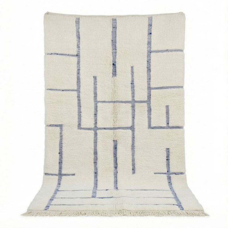 Tapis berbère en laine blanche à motifs graphiques bleus, paré de franges courtes.