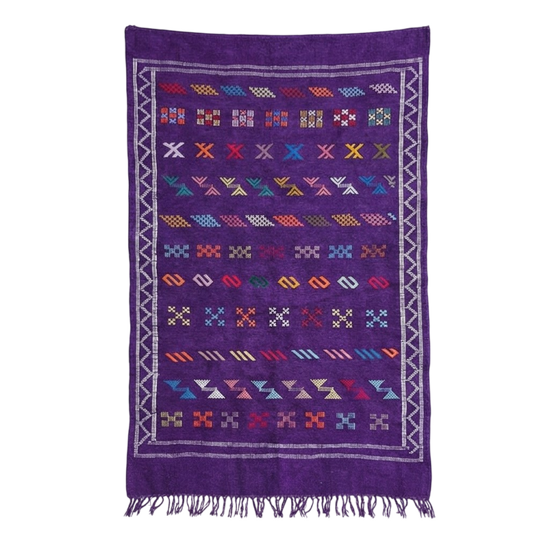 Tapis berbère mauve avec bordure en zigzag, motifs géométriques variés et franges.