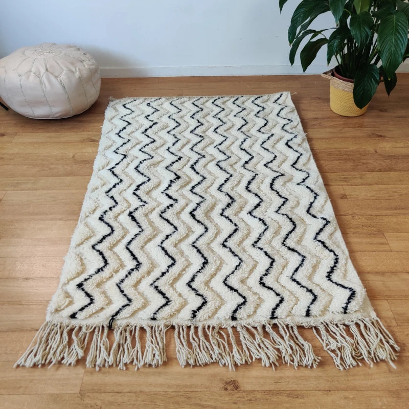 Tapis berbère traditionnel avec motifs ZigZag dynamiques en noir sur fond blanc.
