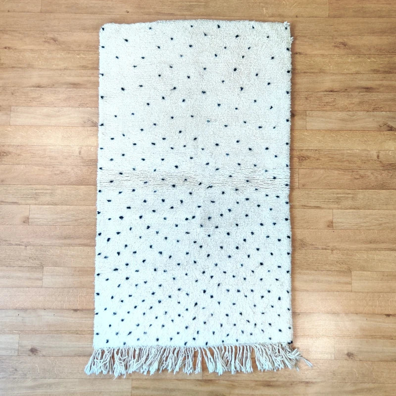Tapis en laine berbère fait main avec design élégant à pois noirs.