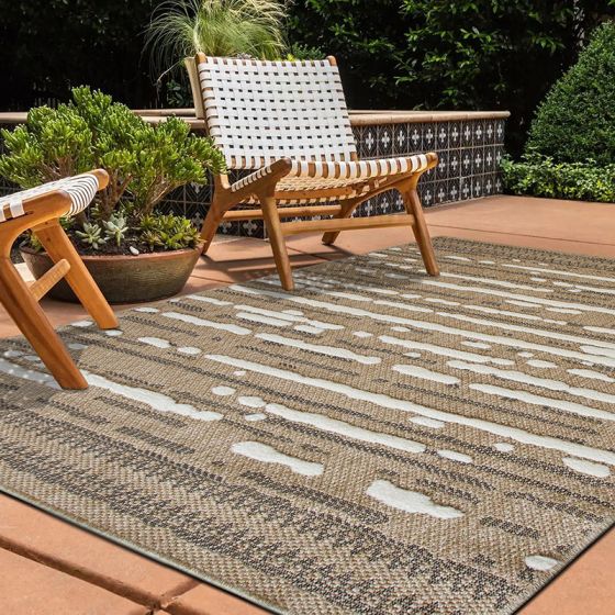 Tapis de jute en relief blanc et noir à motifs de bandes irrégulières sur une terrasse extérieure.