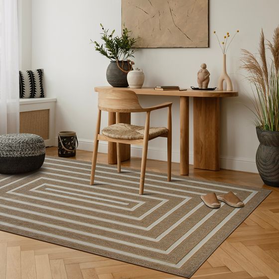 Tapis en jute beige à motif géométrique blanc en forme de labyrinthe, posé sur un parquet en chevrons dans un intérieur minimaliste.