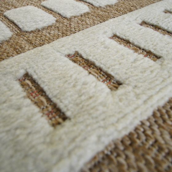 Tapis en jute beige géométrique, avec motifs crème en relief et texture moelleuse contrastante.