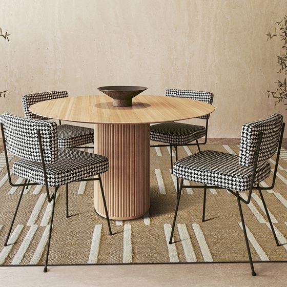 Tapis en jute beige à rayures blanches en relief sous une table en bois et des chaises pied-de-poule.