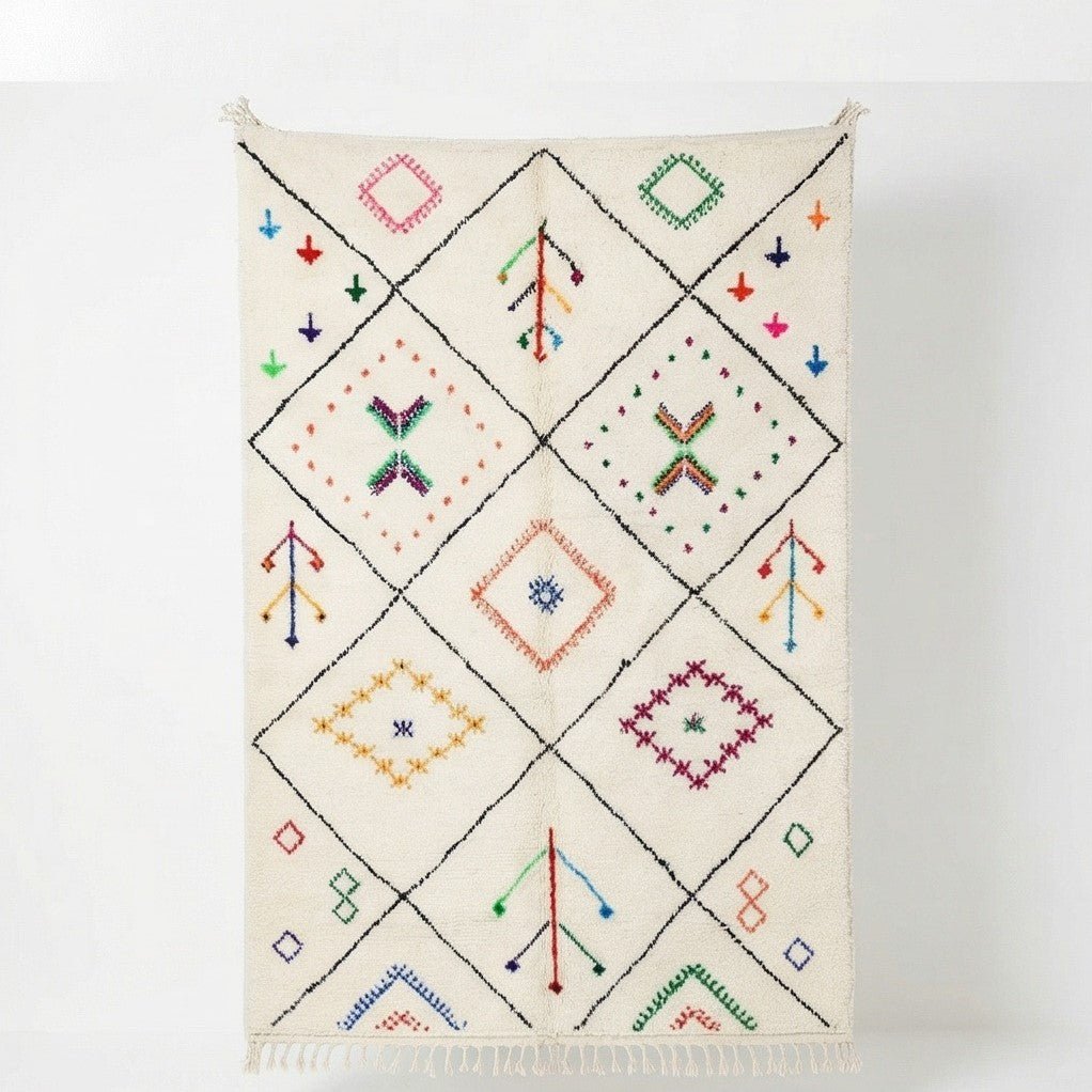 Tapis blanc cassé orné de motifs berbères multicolores dans un quadrillage de losanges noirs.