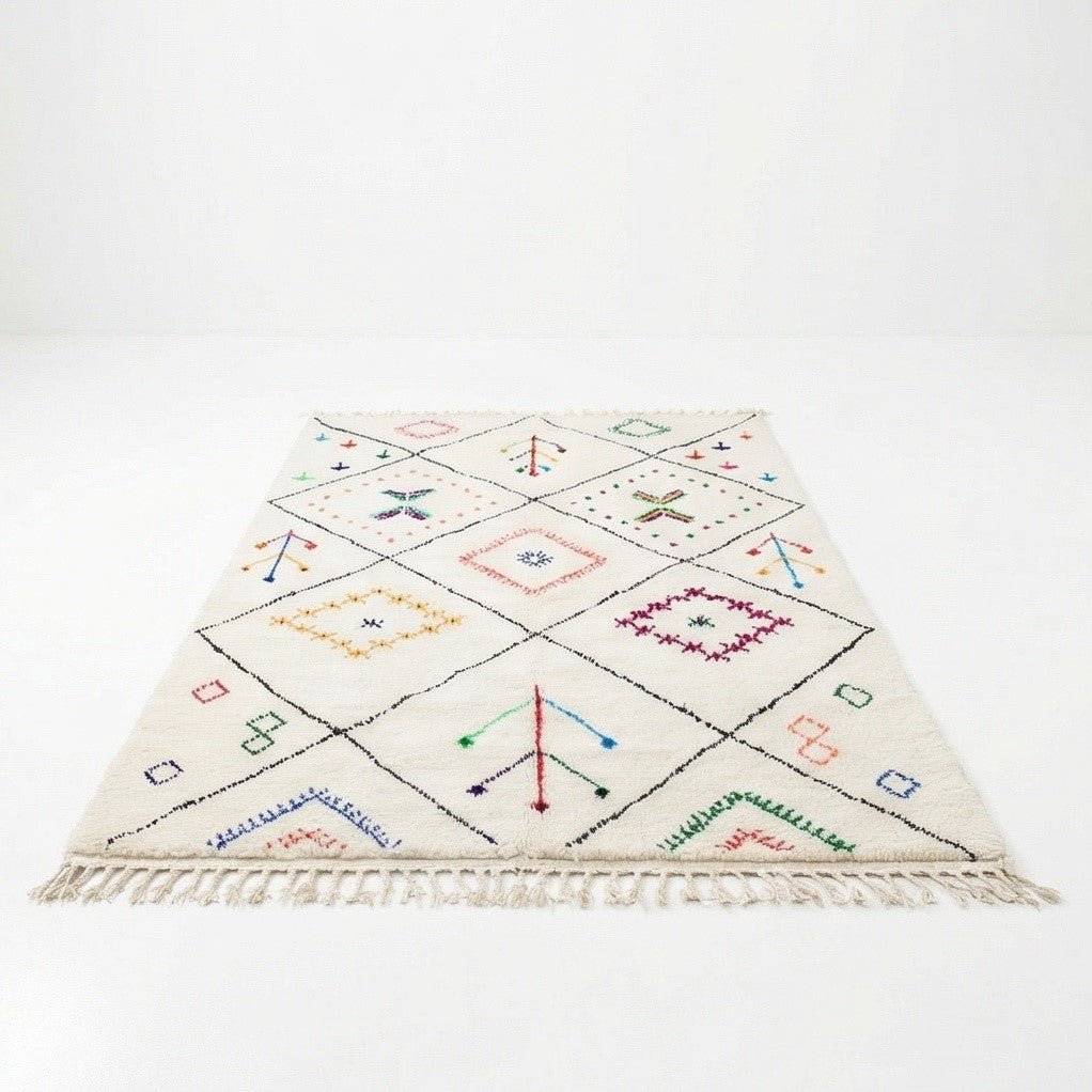 Tapis berbère blanc cassé à motifs géométriques colorés et franges.