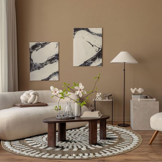 Tapis rond en jute avec motifs en relief blancs, posé sur un parquet dans un salon.