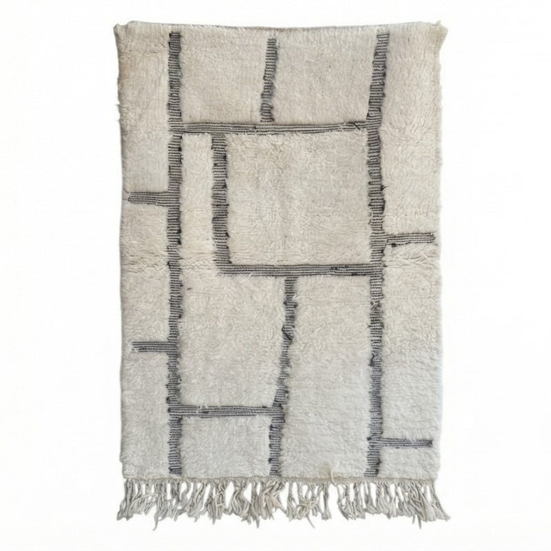 Tapis berbère en laine à motif graphique de style géométrique, orné de franges.
