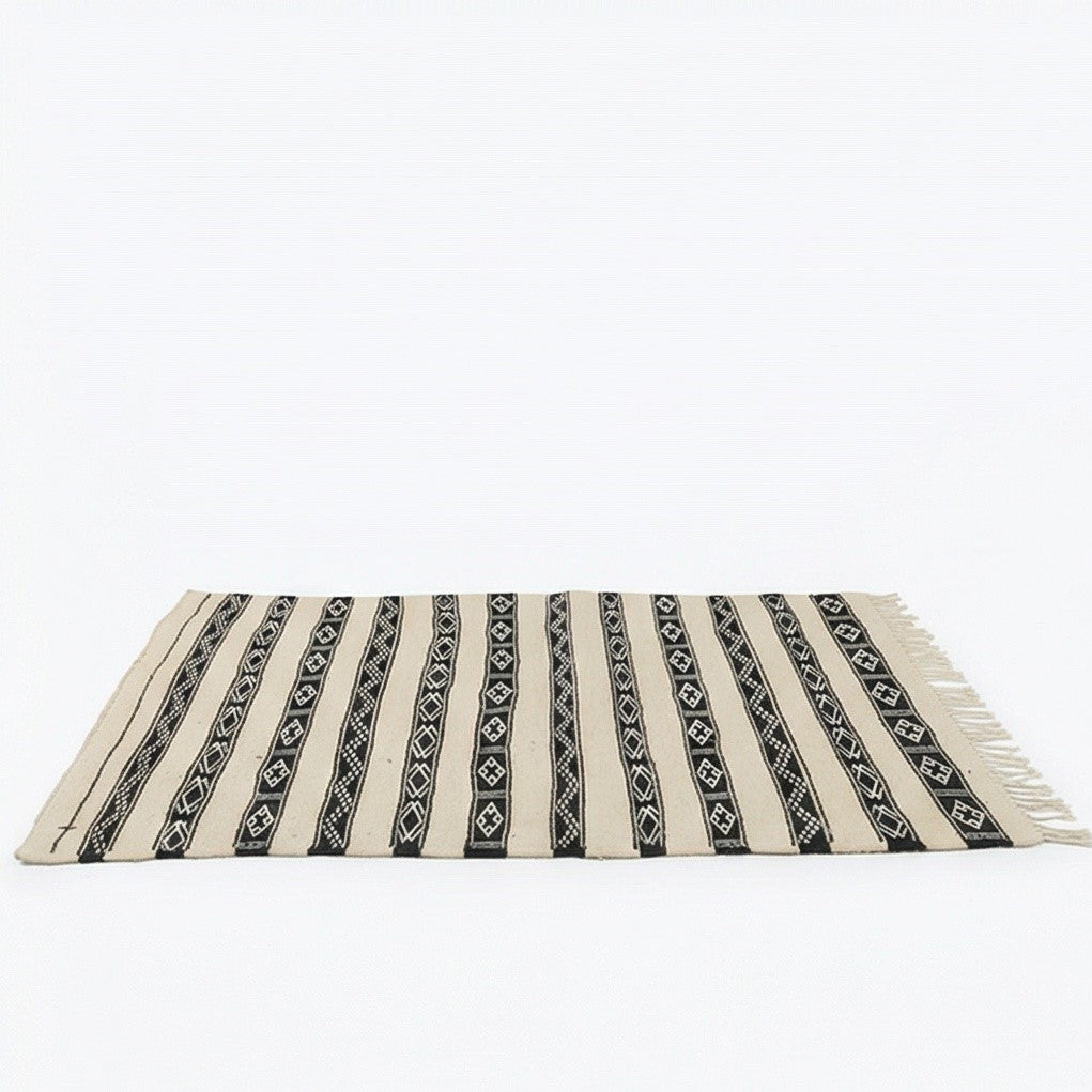 Petit tapis Kilim blanc et noir de style ethnique avec motif rayé et franges décoratives.
