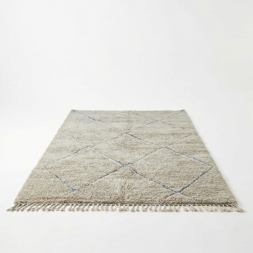 Grand tapis berbère gris à motifs losanges bleus, avec des franges sur les bords.
