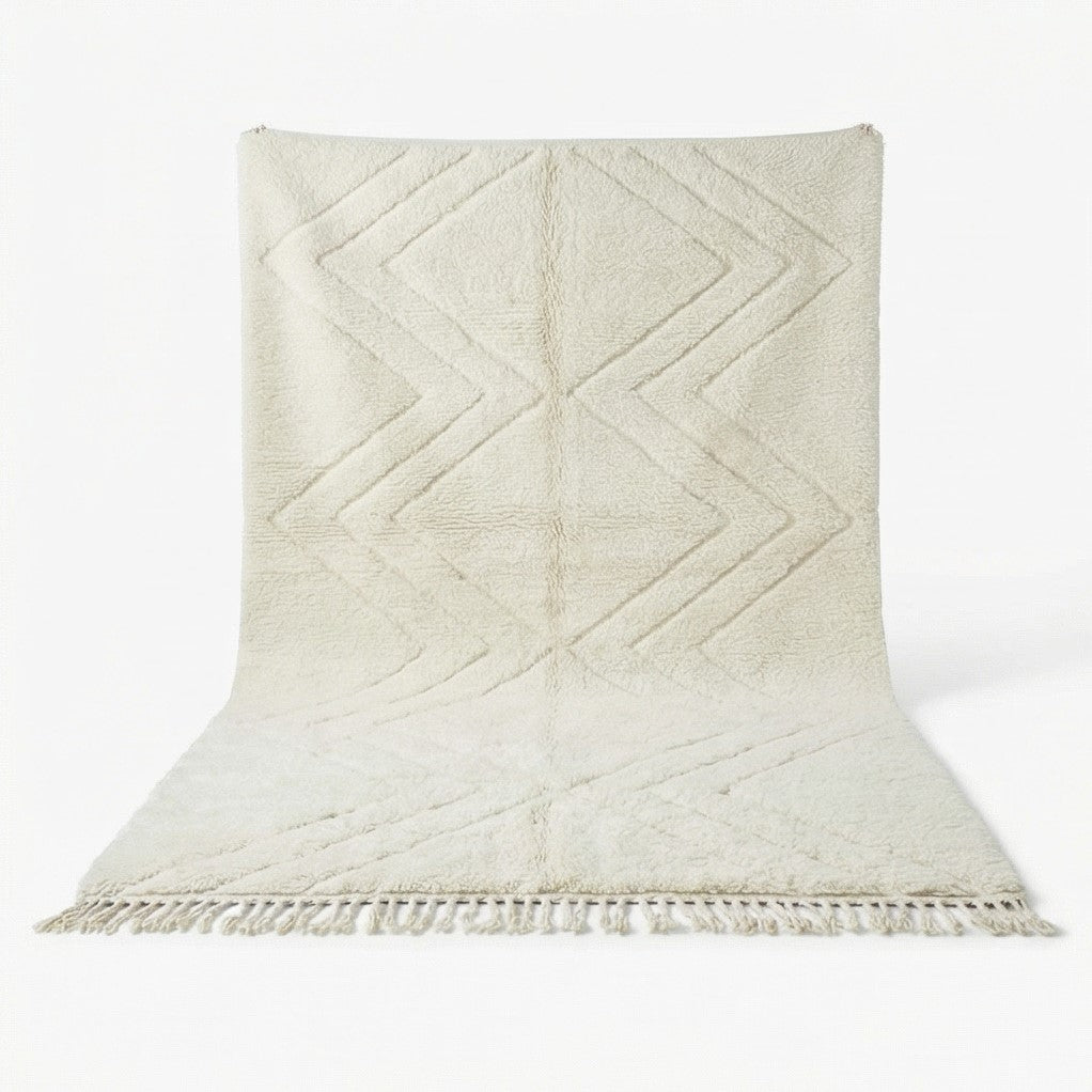 Grand tapis marocain blanc à motif zigzag de style berbère, avec des franges courtes.
