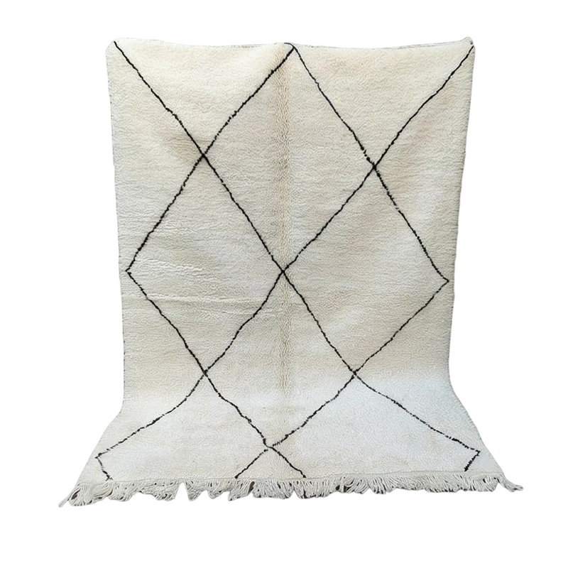 Tapis marocain blanc à losanges noirs parsemés de motifs géométriques traditionnels, avec des franges décoratives.
