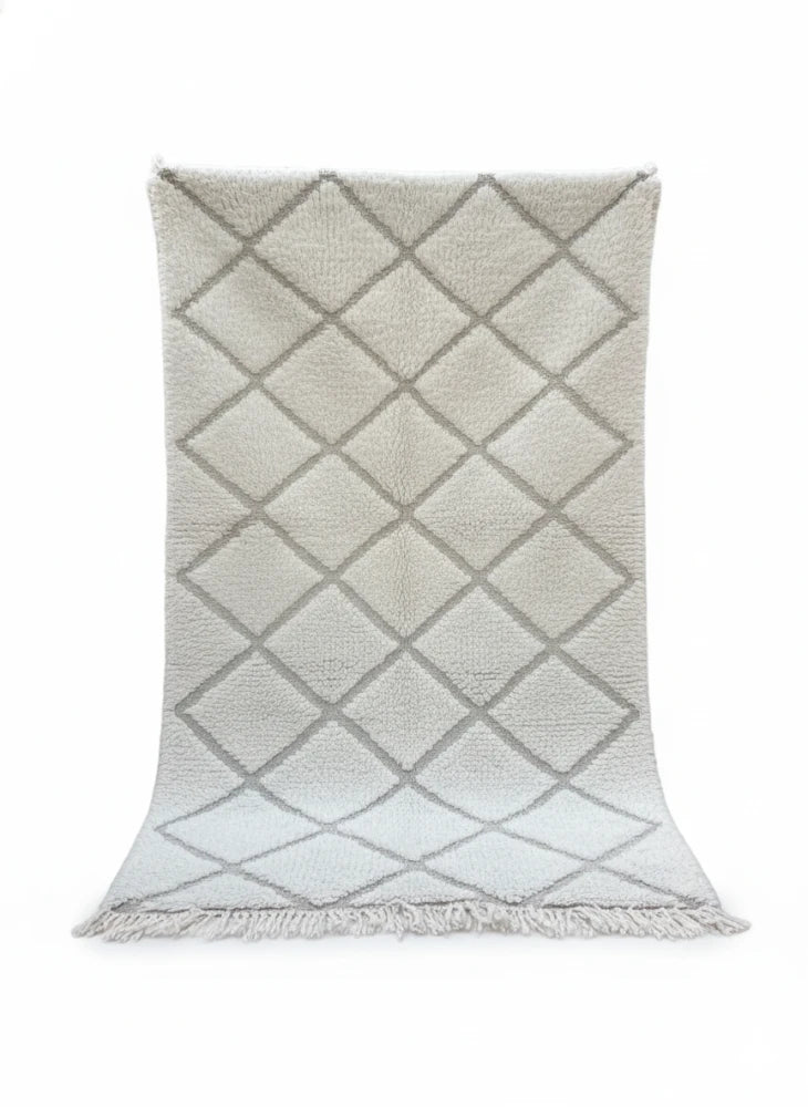 Petit tapis à losanges blancs de style berbère, avec un motif géométrique losangé ton sur ton et des franges.

