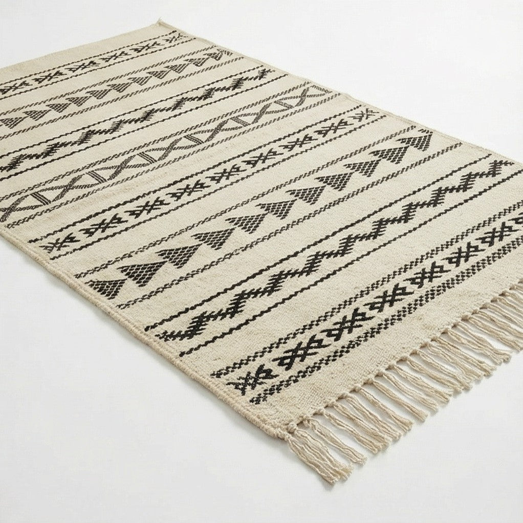 Petit tapis kilim tribal écru et noir, à motifs géométriques et franges décoratives.
