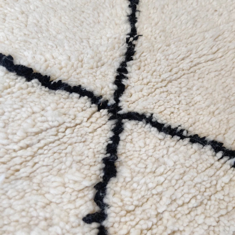 Gros plan sur les motifs de croix noires du tapis berbère soulignant l'artisanat délicat