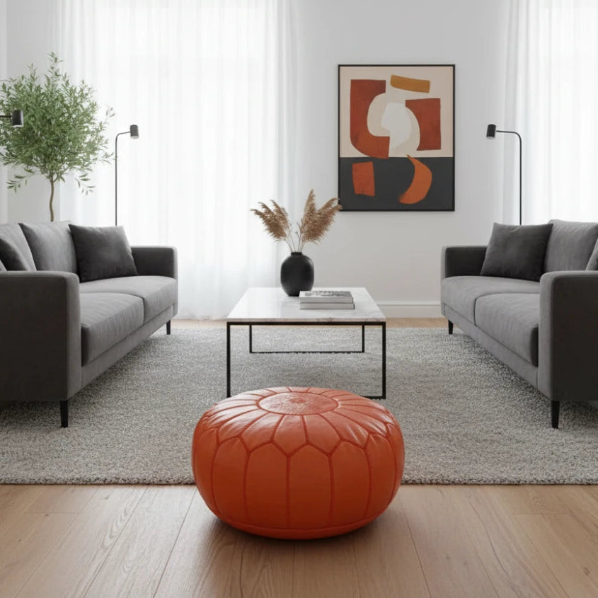 Pouf marocain orange de couleur vive, en cuir texturé avec couture décorative.