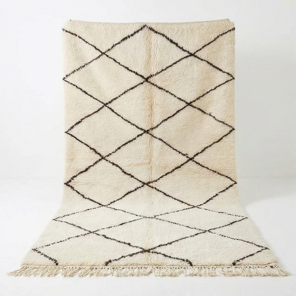Tapis berbère blanc à motifs losanges noirs, de texture moelleuse et franges décoratives.
