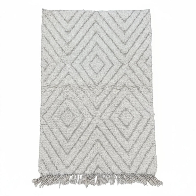 Petit tapis berbère blanc à losanges parsemés de franges décoratives.
