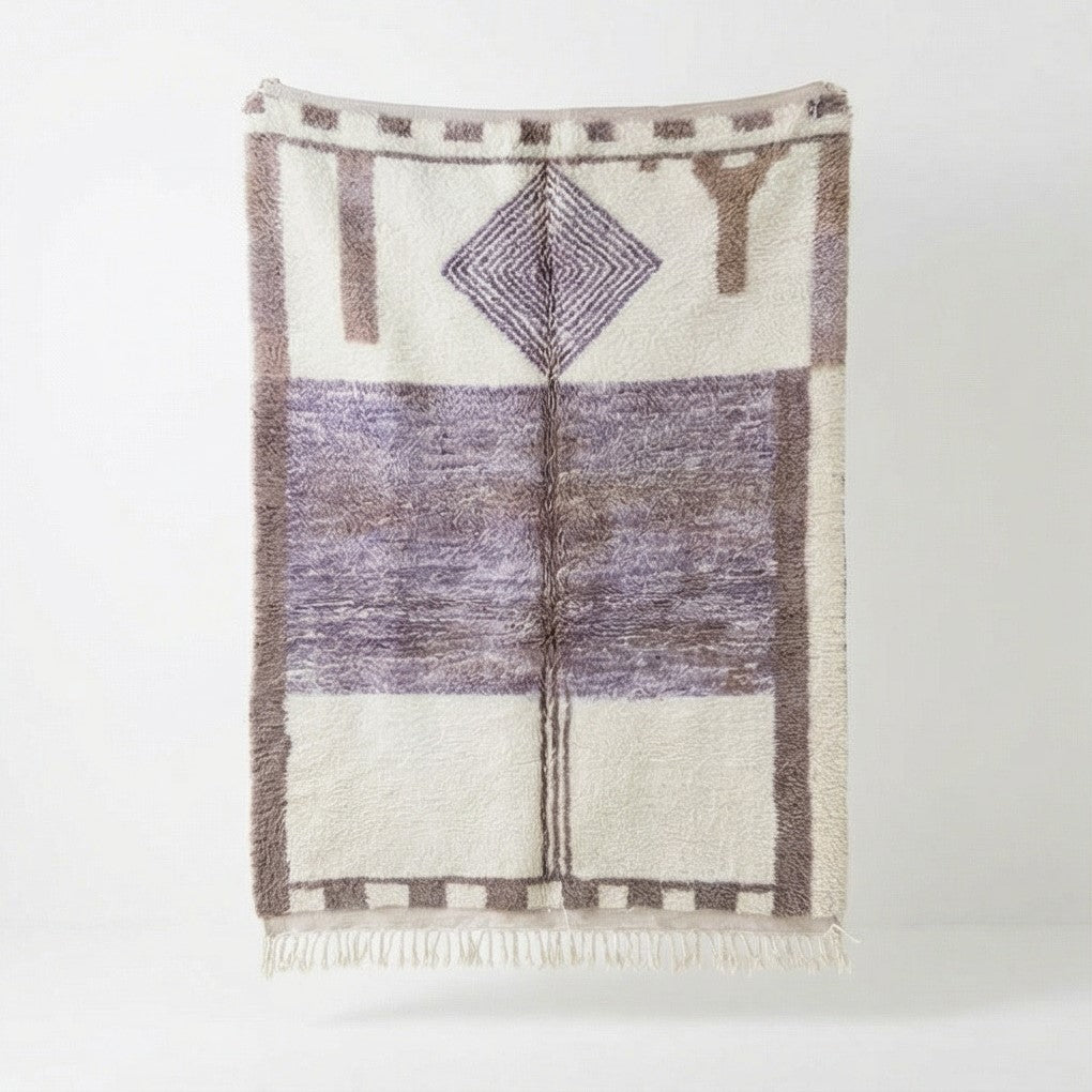 Tapis berbère en laine violet, de motif géométrique, avec des détails de franges.