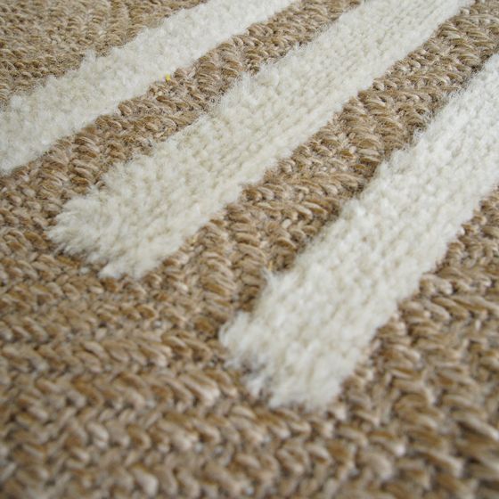 Tapis en jute beige avec de larges rayures blanches en relief, montrant une texture tissée.