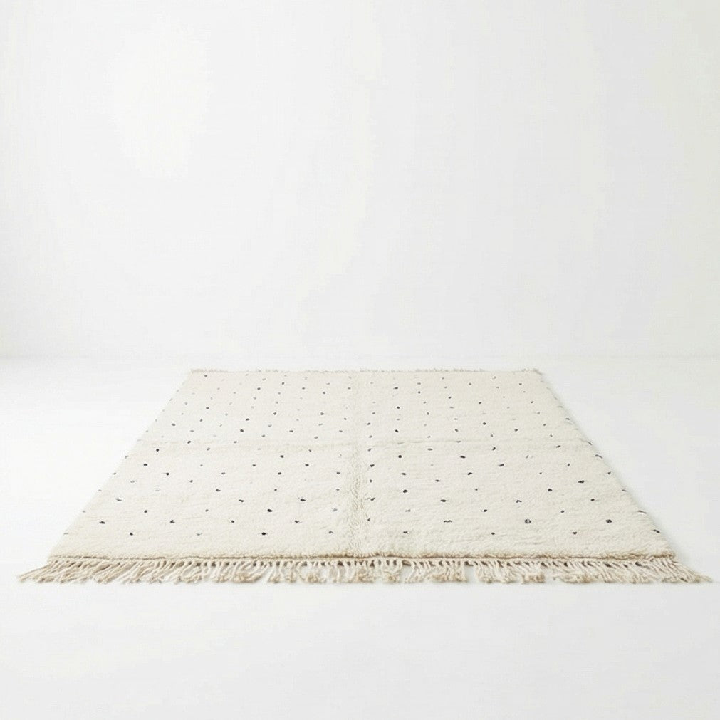 Tapis marocain écru à pois noirs de 150x250 cm, avec des franges décoratives.