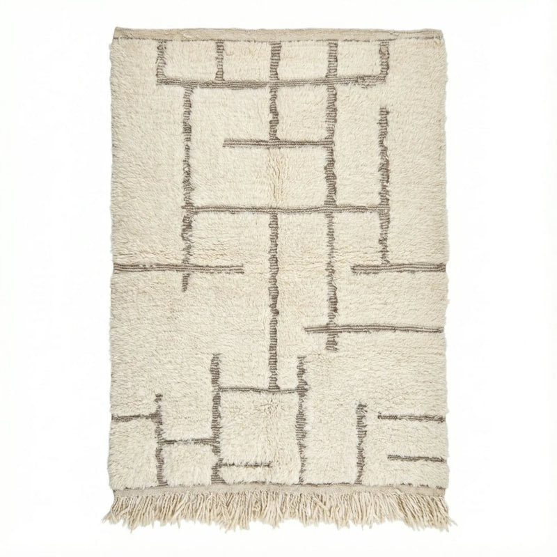 Tapis berbère blanc à motifs graphiques noirs de style tribal, avec franges.
