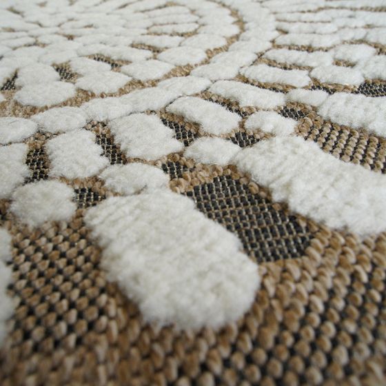 Tapis rond en jute avec motifs blancs en relief doux et texturés, sur fond tissé beige et foncé.